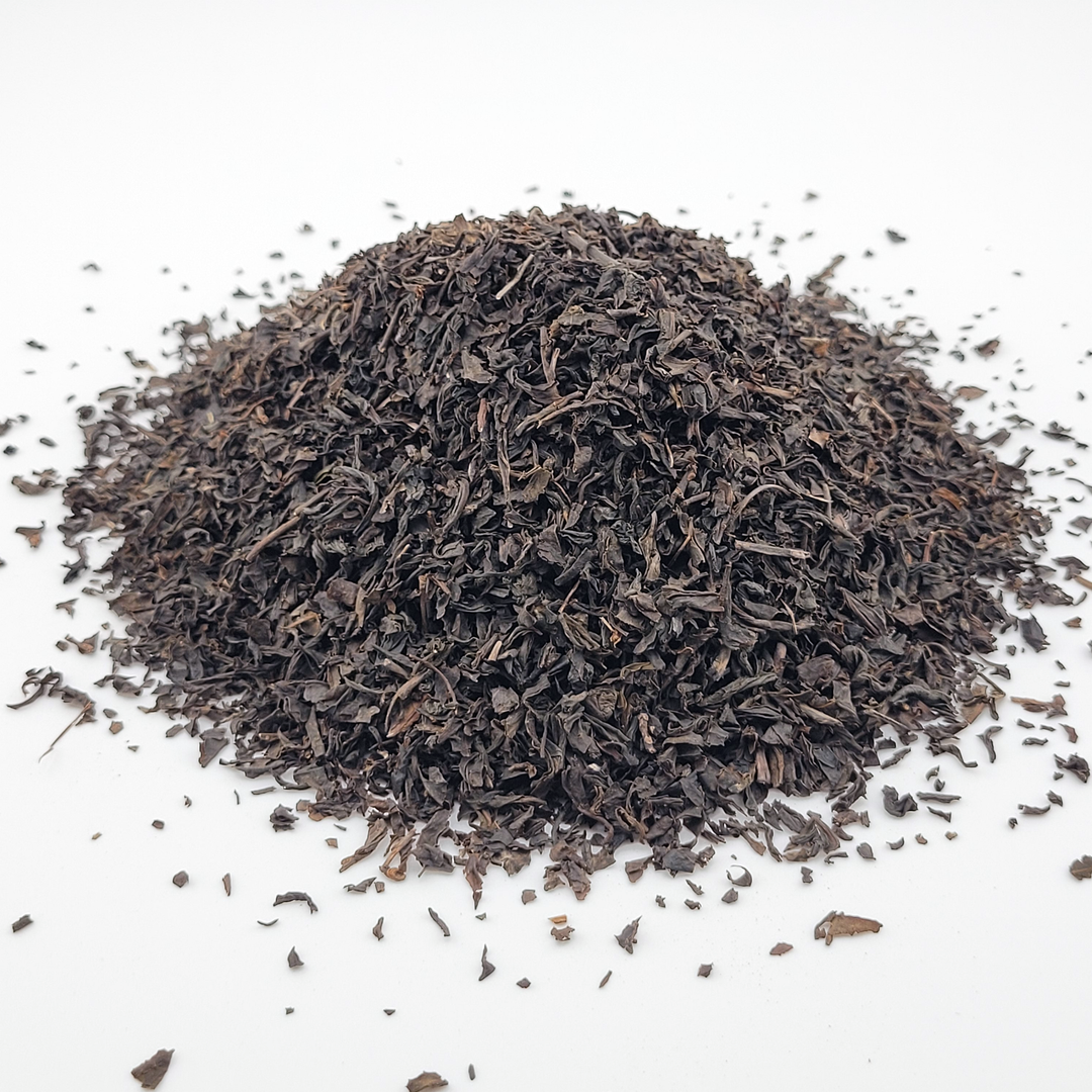 Pile of dried black tea leaves on a white background