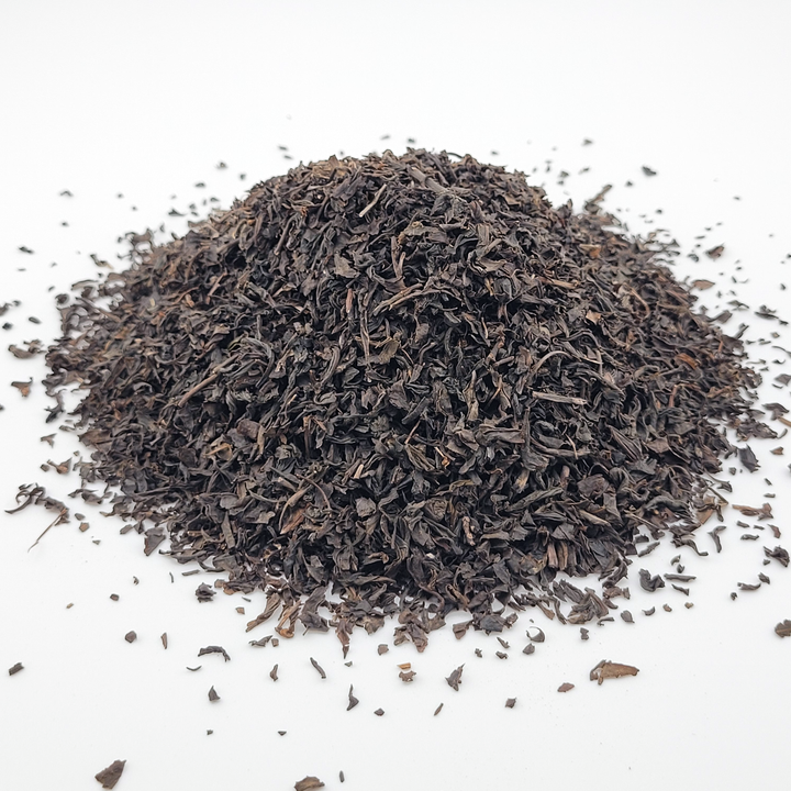 Pile of dried black tea leaves on a white background