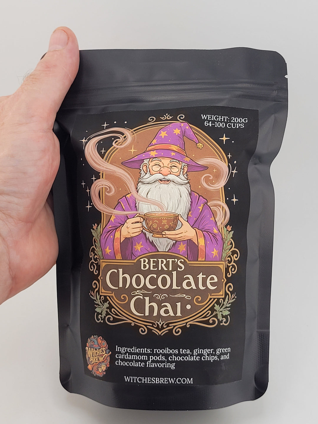 Hand holding a package of Bert's Chocolate Chai on a light gray background