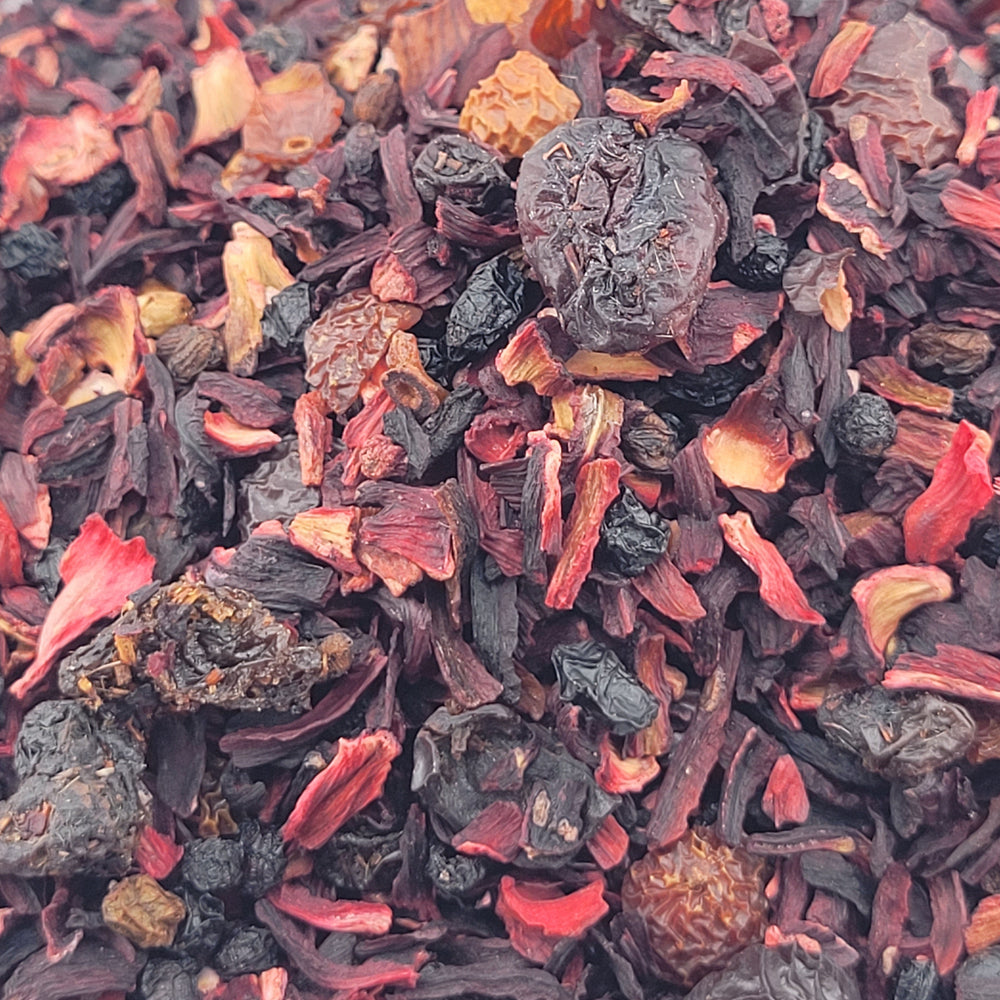 Close-up of a mix of Crimson Zing dried fruits and herbs with red, black, and orange colors.