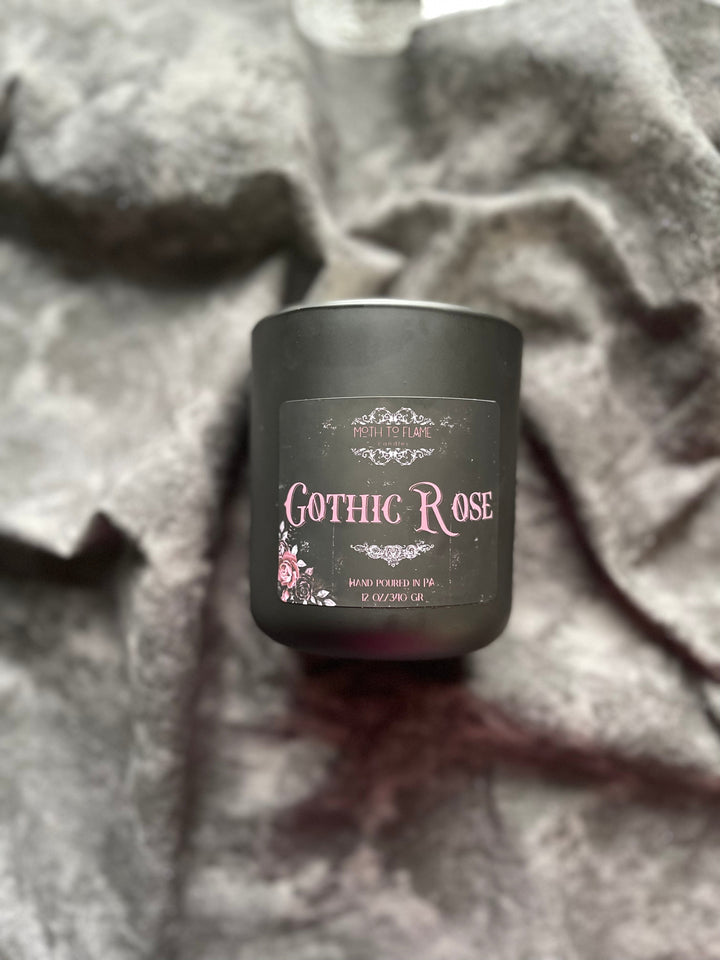 Black candle labeled 'Gothic Rose' on a textured fabric background