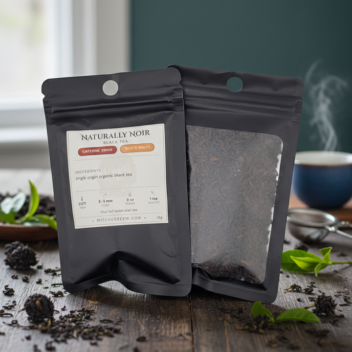 Two black tea packages from Naturally Noir on a wooden surface with tea leaves and a cup in the background.